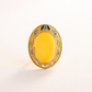 Decorative oval butterscotch amber ring with a yellow center and gold rim on a white background