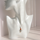 A silver pendant amber necklace with a small octopus, displayed on a white ceramic mannequin bust against a soft beige background.