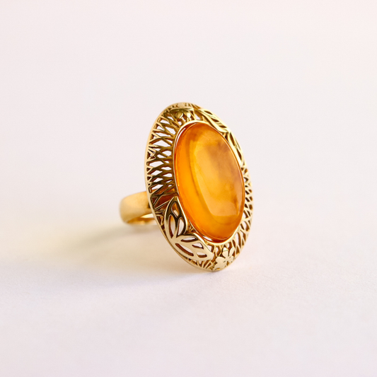 Gold amber ring with a yellow gemstone on a light background