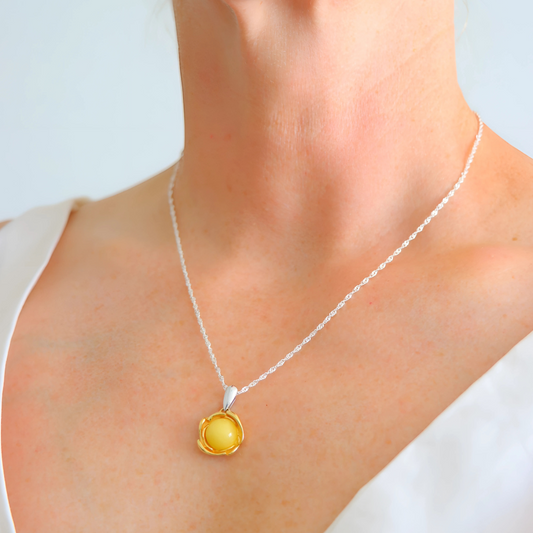 Necklace with a yellow pendant worn by a person on a white background