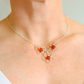 Silver amber flower necklace with orange beads worn by a person