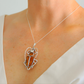 Necklace with a scarab pendant featuring amber stones on a person wearing a white top.