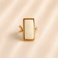 Front view of white amber ring with rectangular stone and gold-tone frame.