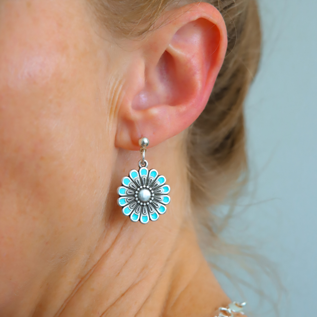 Close-up of a woman's ear wearing a  earring with turquoise accents from flower jewelry set
