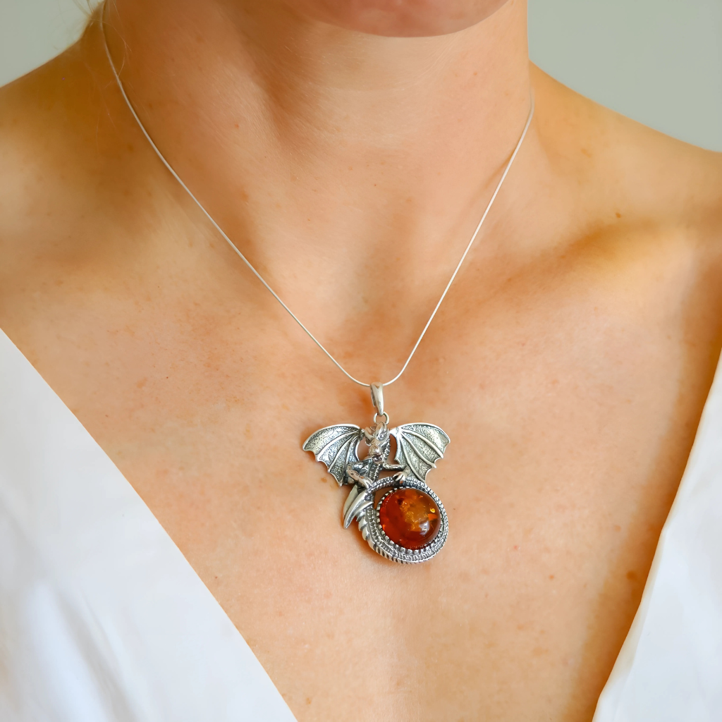Silver Dragon pendant with a red stone on a necklace worn by a person