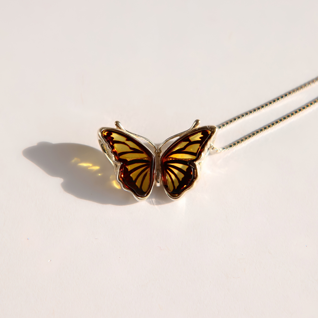 Silver amber butterfly necklace with sterling silver chain bracelet on a white background