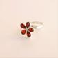 Silver amber ring with red gemstones on a beige background
