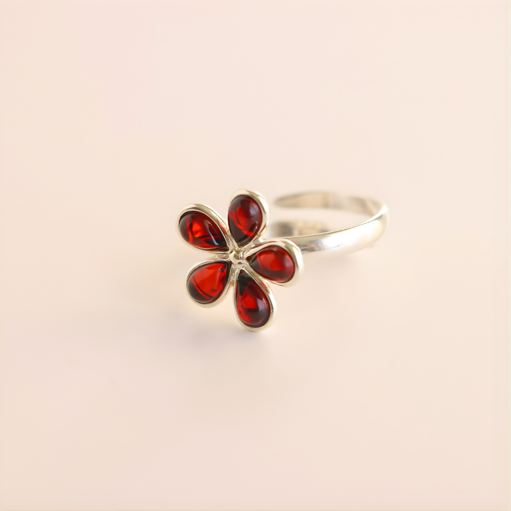 Silver amber ring with red gemstones on a beige background