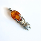 Amber pendant with silver beetle design on a white background