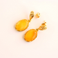 Gold earrings with yellow stones on a light beige background