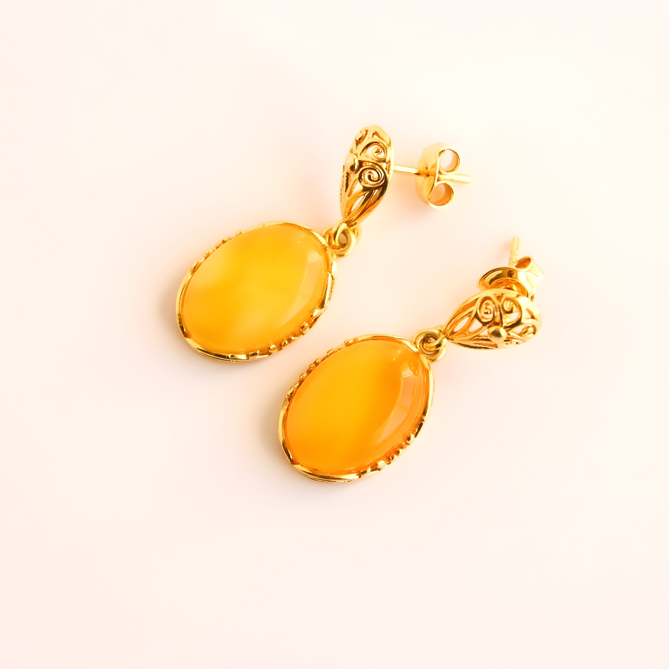 Gold earrings with yellow stones on a light beige background