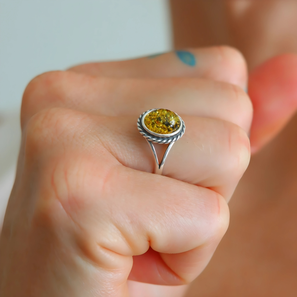 Close-up of a hand wearing a silver oval cut ring with a green gemstone.