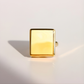 Gold square-shaped amber ring on a light gray background
