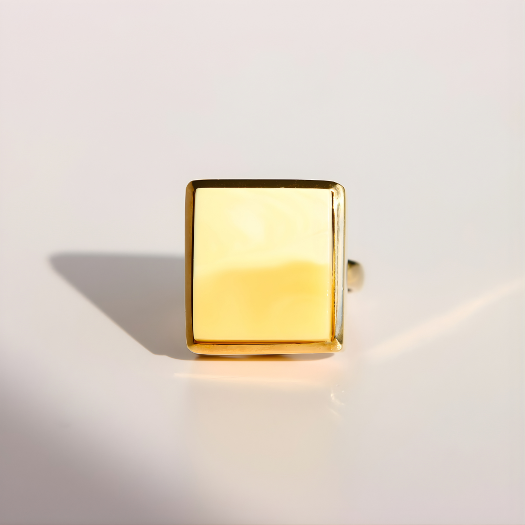 Gold square-shaped amber ring on a light gray background