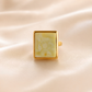 Gold amber ring with a square stone on a beige fabric background