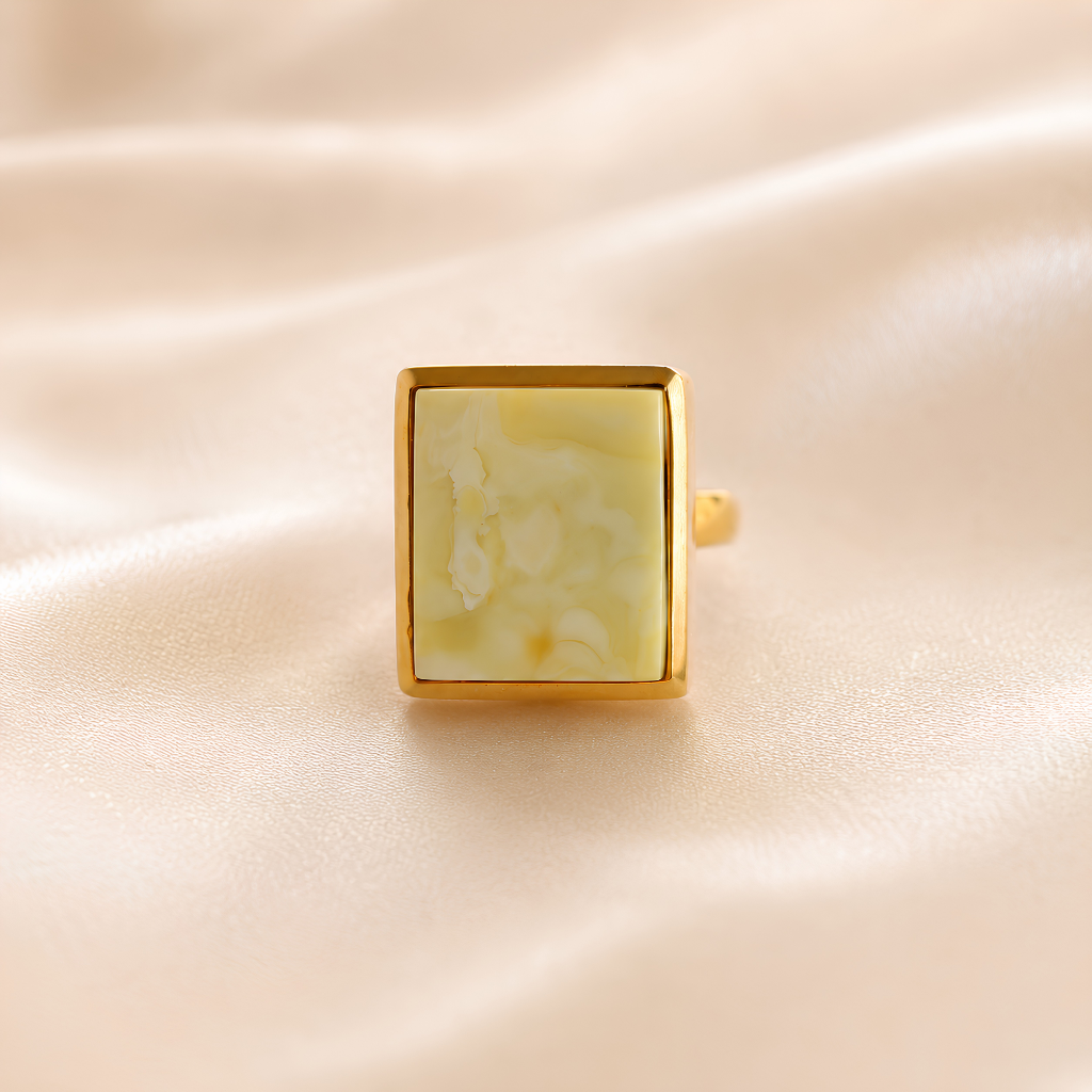 Gold amber ring with a square stone on a beige fabric background