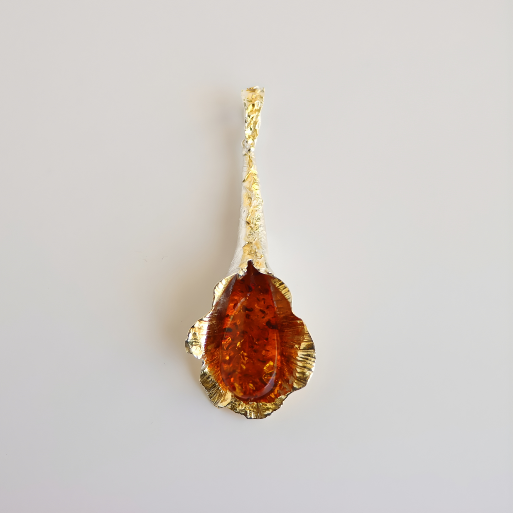 Gold amber necklace  with a brown gemstone on a light gray background
