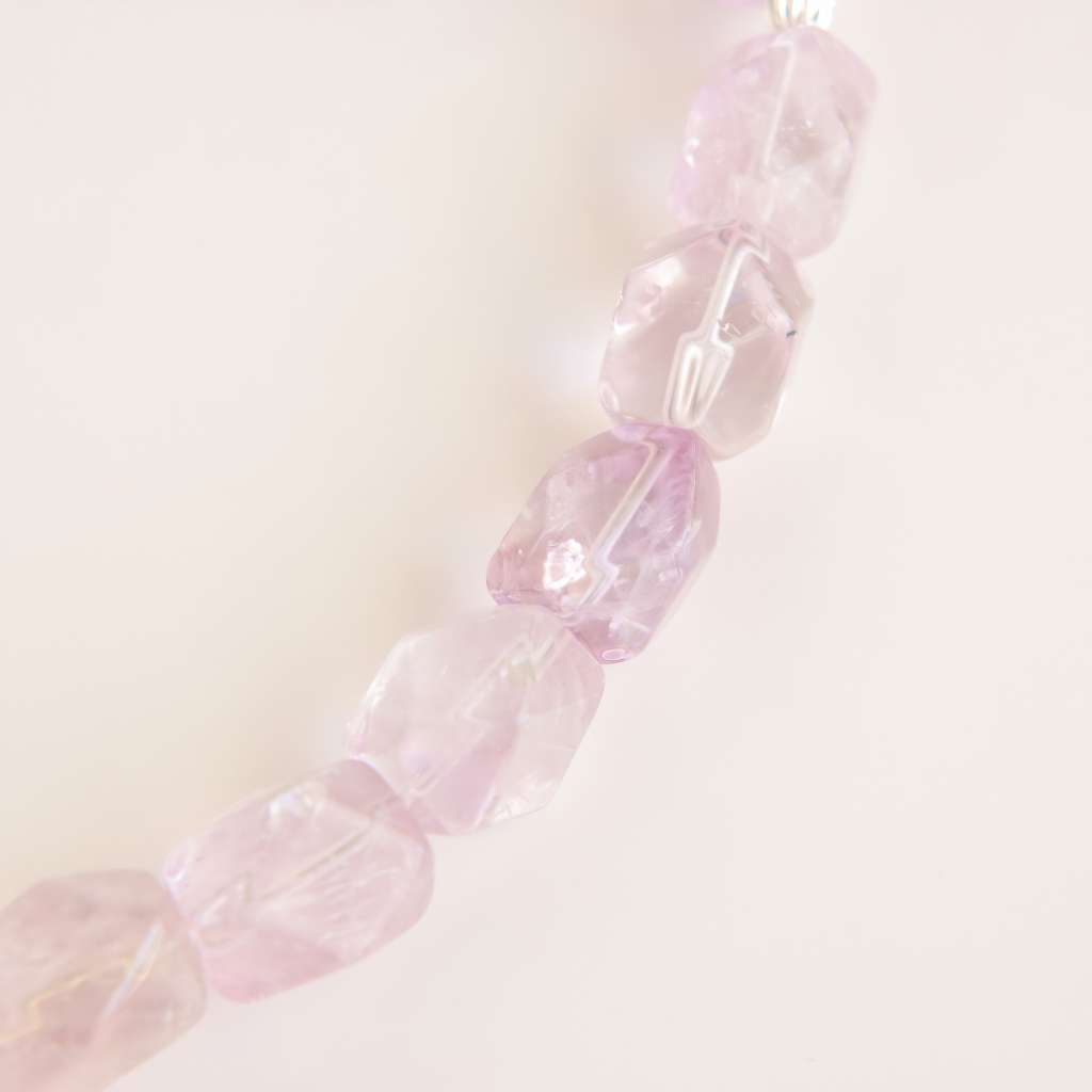 Close-up of a choker necklace with purple gemstone beads on a light background