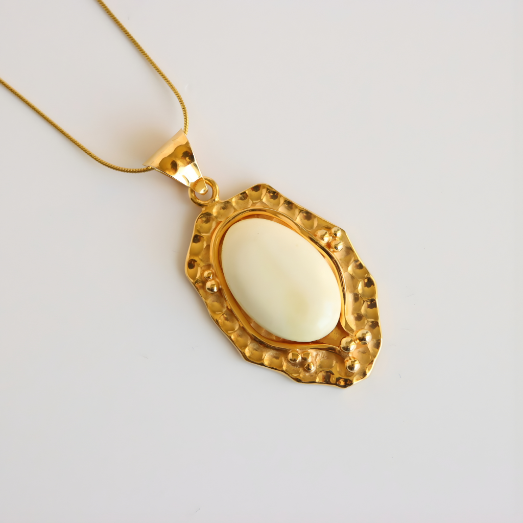 Gold amber necklace pendant with a white stone on a light gray background
