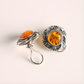 Pair of silver clip on earrings with amber stones on a light background