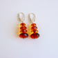 amber drop earrings on white background. red and orange gemstones.