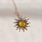 A silver lemon Baltic amber sun pendant necklace with a yellow amber center, shown on a plain light background.