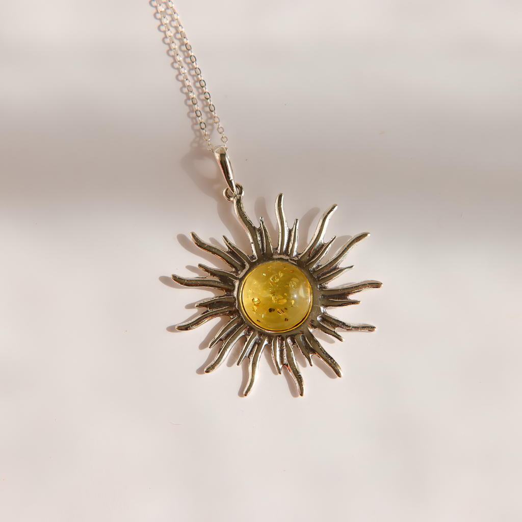 A silver lemon Baltic amber sun pendant necklace with a yellow amber center, shown on a plain light background.