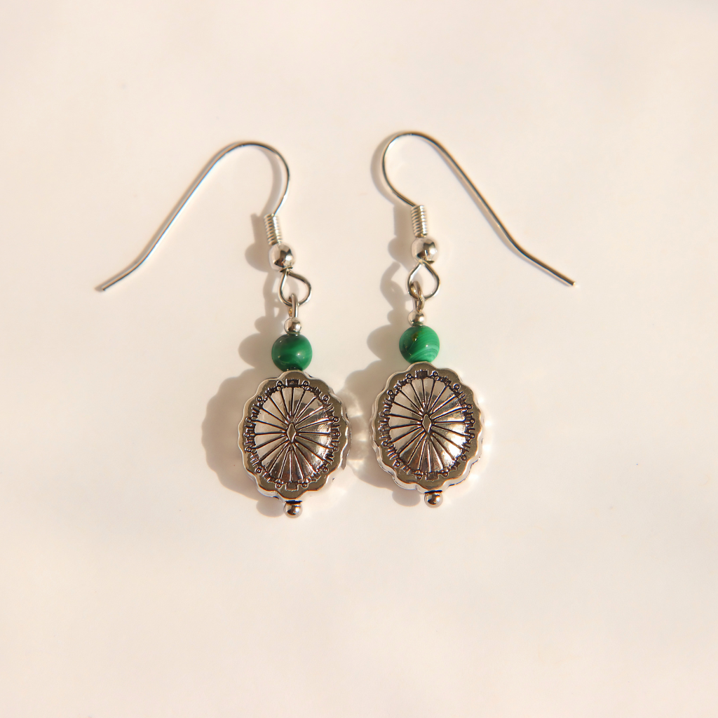 A pair of silver-toned western malachite dangle earrings with green beads and oval wheel-like charms, photographed on a plain light background.