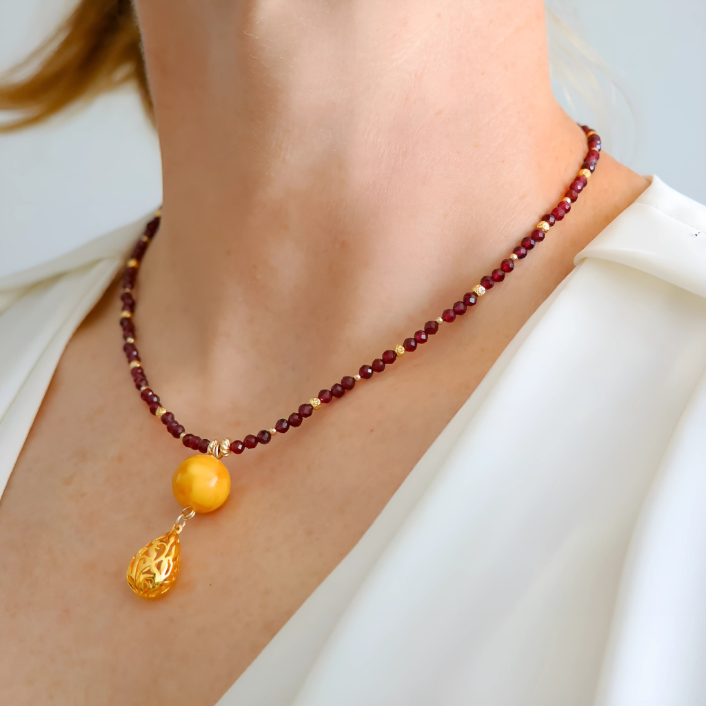 Close-up of Baltic butterscotch amber and garnet with gold-filled pendant