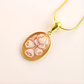 Gold flower necklace with floral cameo design on a white background