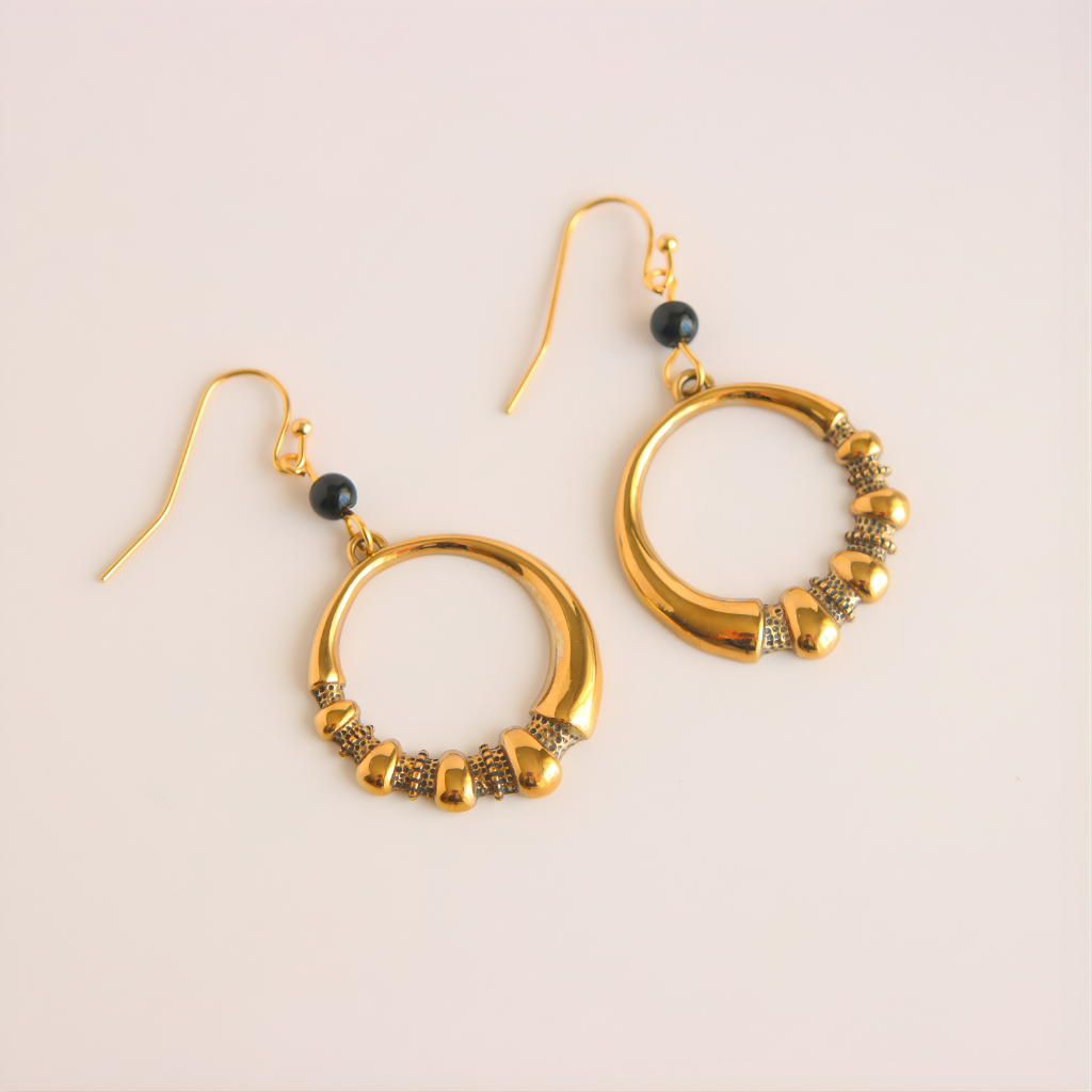 Gold hoop earrings with beads on a beige background