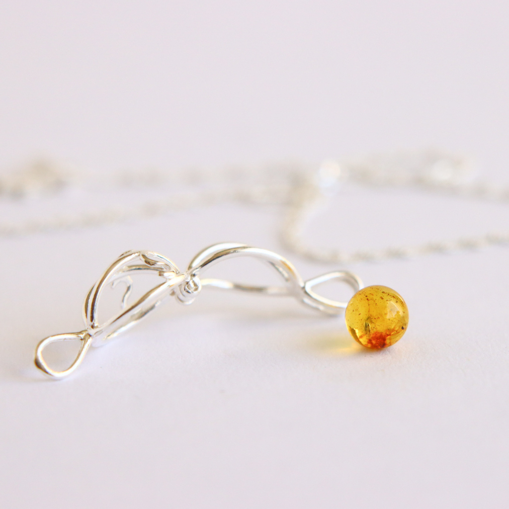 Silver cage pendant with a yellow gemstone on a light background