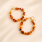 Pair of Baltic amber hoop earrings with amber-colored beads on a beige background