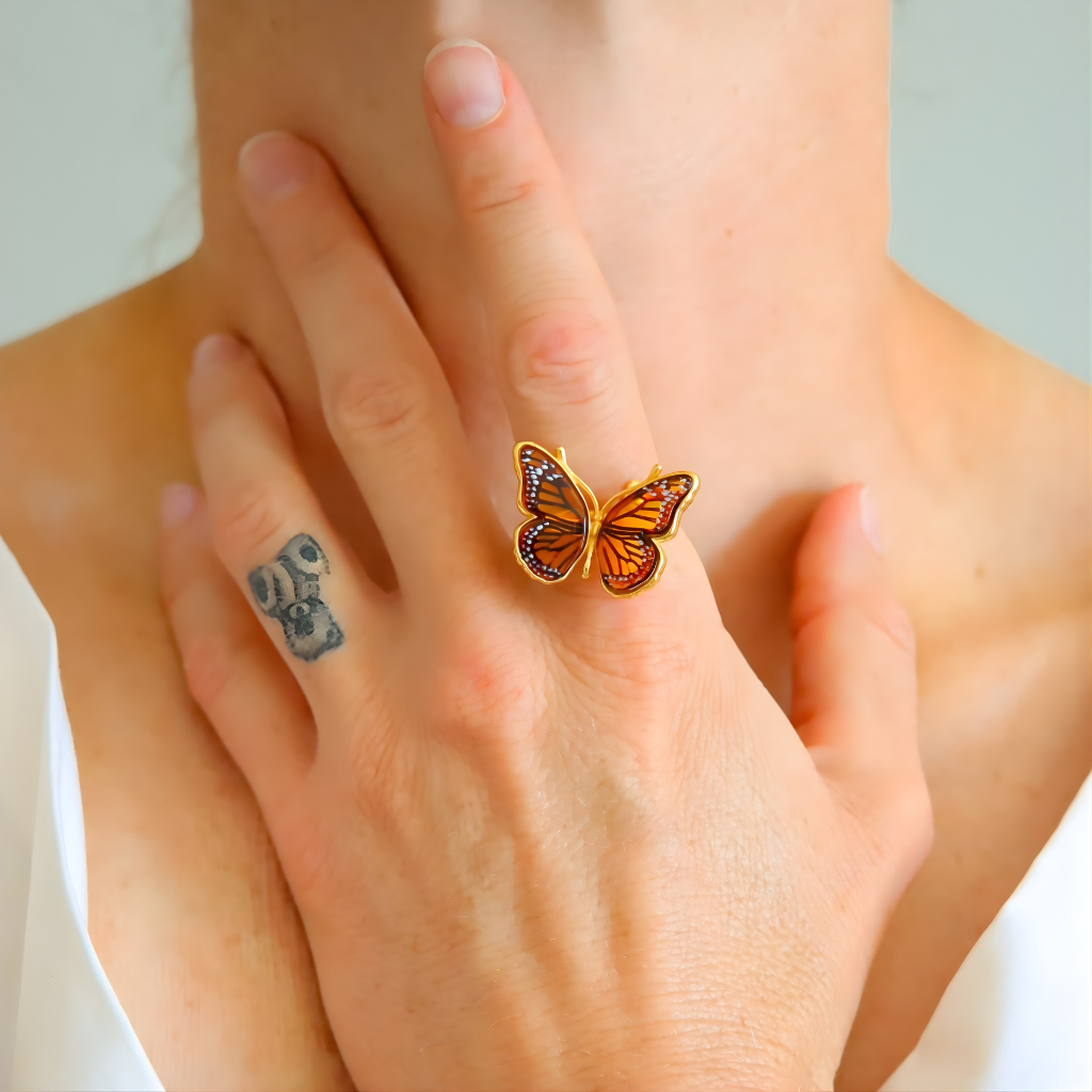 Butterfly ring on a person's finger with a tattoo on the other hand