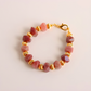 Bracelet with pink Botswana agate beads and gold accents on a light pink background