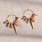 A pair of gold kunzite dagger hoop earrings with dangling pale pink stone beads and cream-colored cone charms, displayed on a warm off-white background with soft shadows.