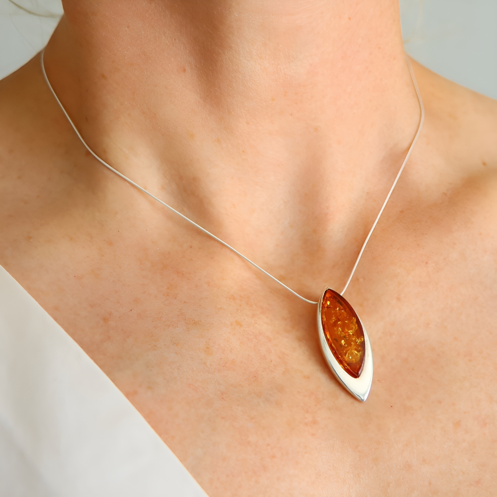 sterling silver necklace with a amber pendant on a person's neck against a neutral background