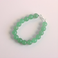 Green beaded jade bracelet on a light pink background