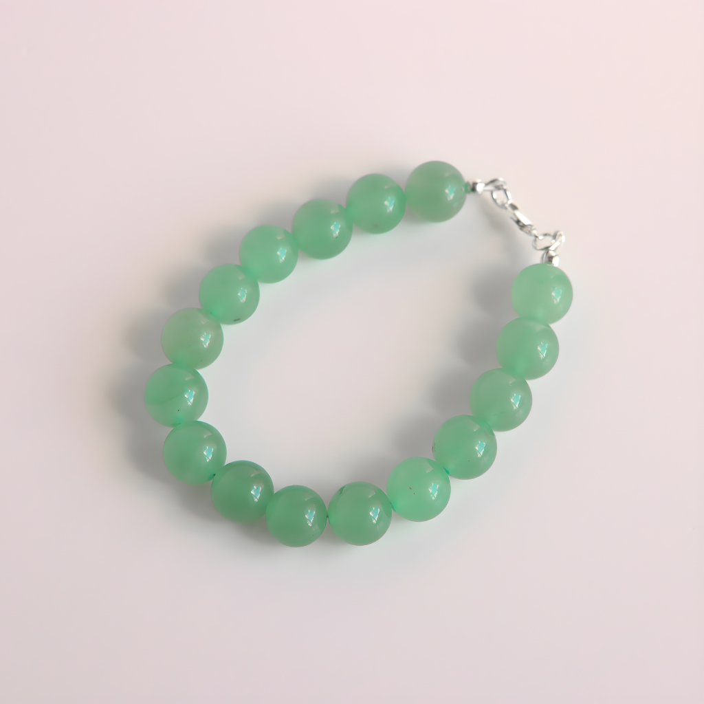 Green beaded jade bracelet on a light pink background