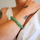 Green beaded jade bracelet on a wrist with tattoos visible