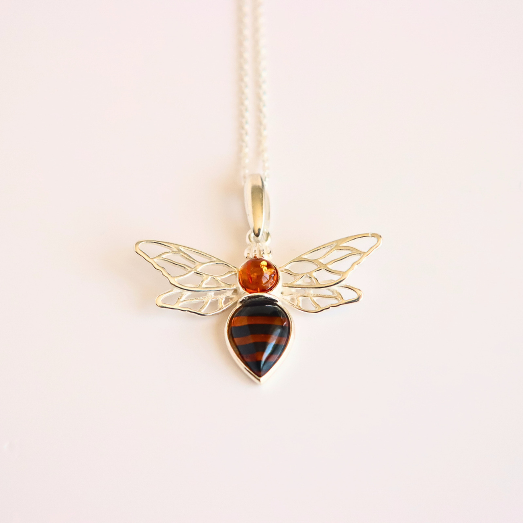 silver amber bee pendant with amber-colored heart and orange gemstone on a white background. amber bee necklace