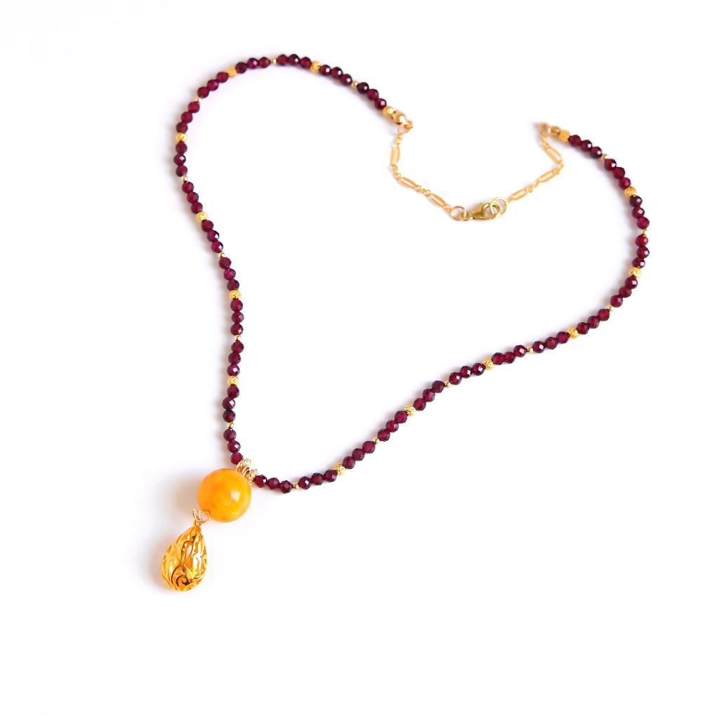 Detailed view of 14k gold-filled butterscotch amber necklace pendant with garnet strand
