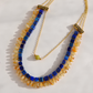 Close-up of a lapis, citrine, and olive jade statement necklace with gold plated brass chain and decorative pewter connectors.