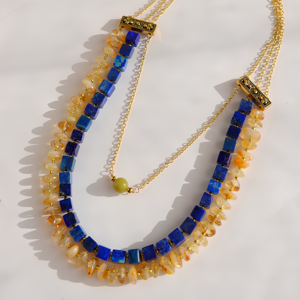 Close-up of a lapis, citrine, and olive jade statement necklace with gold plated brass chain and decorative pewter connectors.