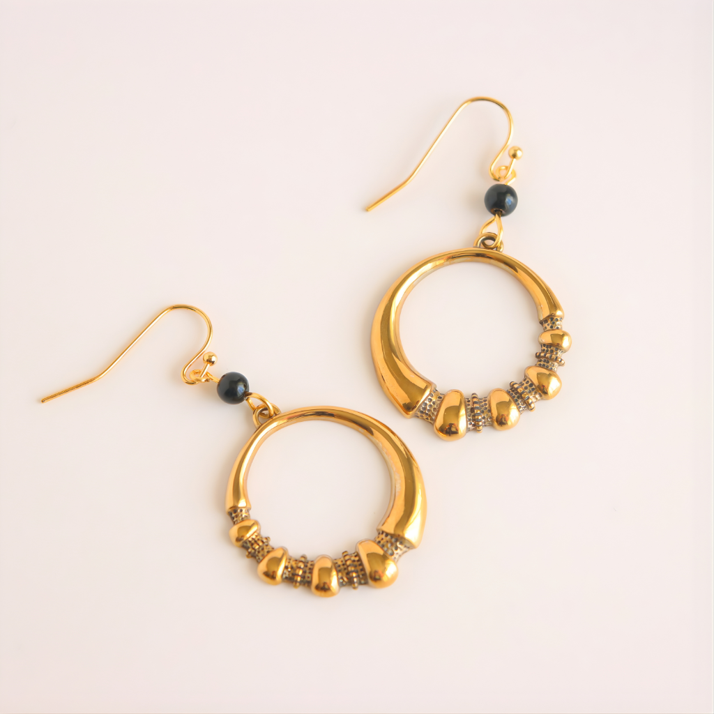 Gold hoop earrings with beads on a light background