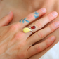 Close-up of a hand wearing a colorful sterling silver ring with water droplet design.