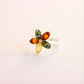 Multicolored gemstone amber ring on a light pink background