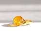 A gold ring featuring a large, polished amber gemstone with a circular cutout detail, photographed on a clean white surface with soft shadows.