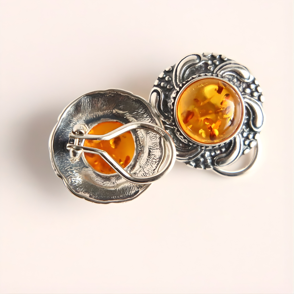 Pair of silver clip on earrings with amber stones on a light background