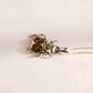 A silver beetle-shaped pendant amber necklace with three amber-colored gemstones, shown on a plain white background.